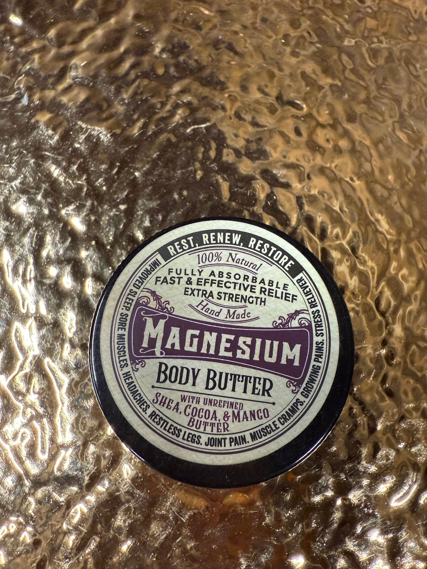 Round container labeled 'Magnesium Body Buffer' on a textured metallic surface