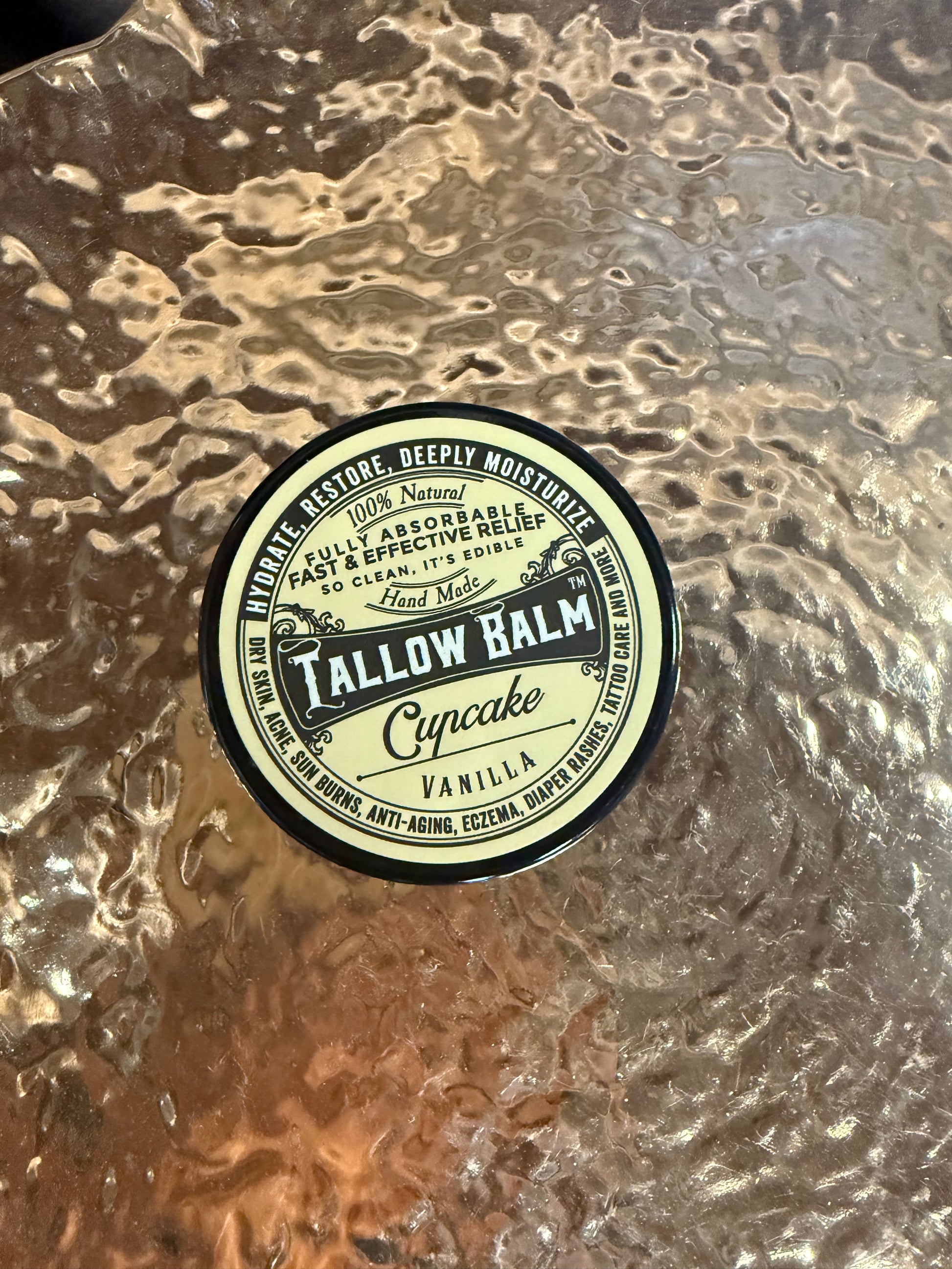 Round label on a textured surface with 'Tallow Balm' text