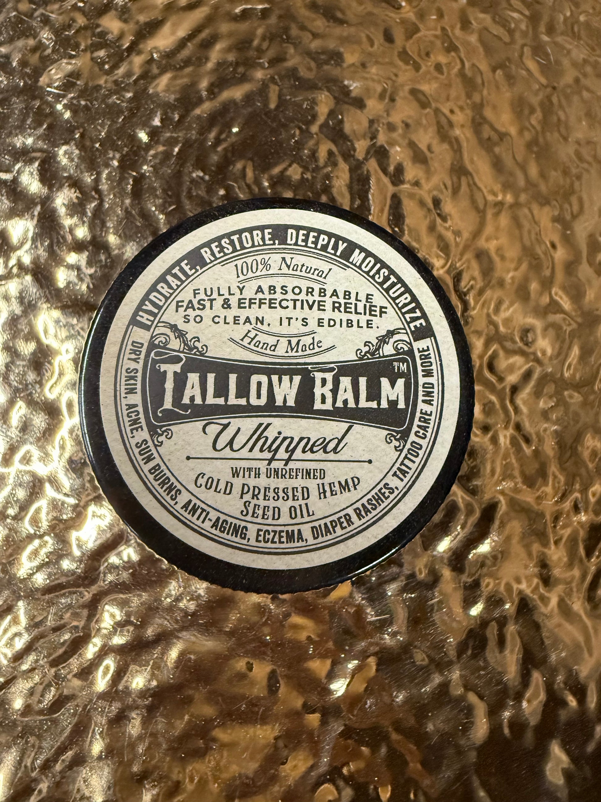 Tallow balm container with label on a textured gold background