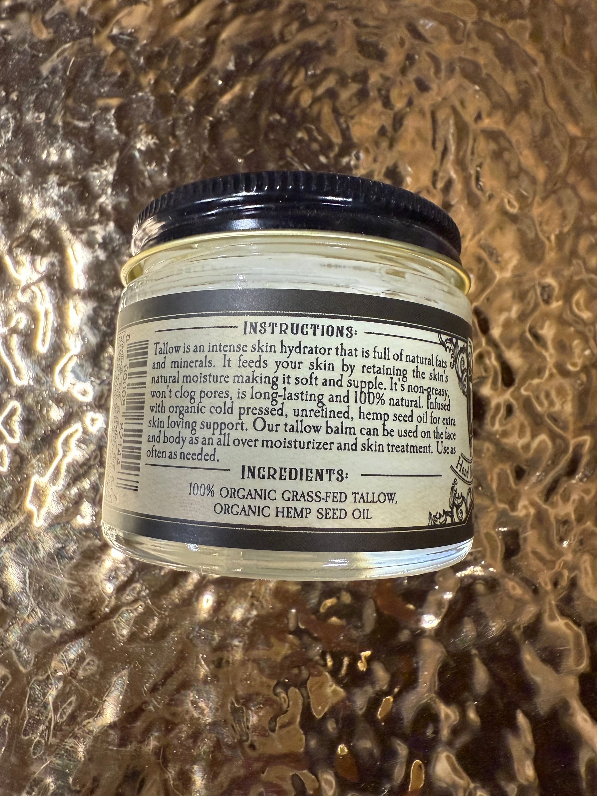 Jar of tallow balm with label on a textured gold background